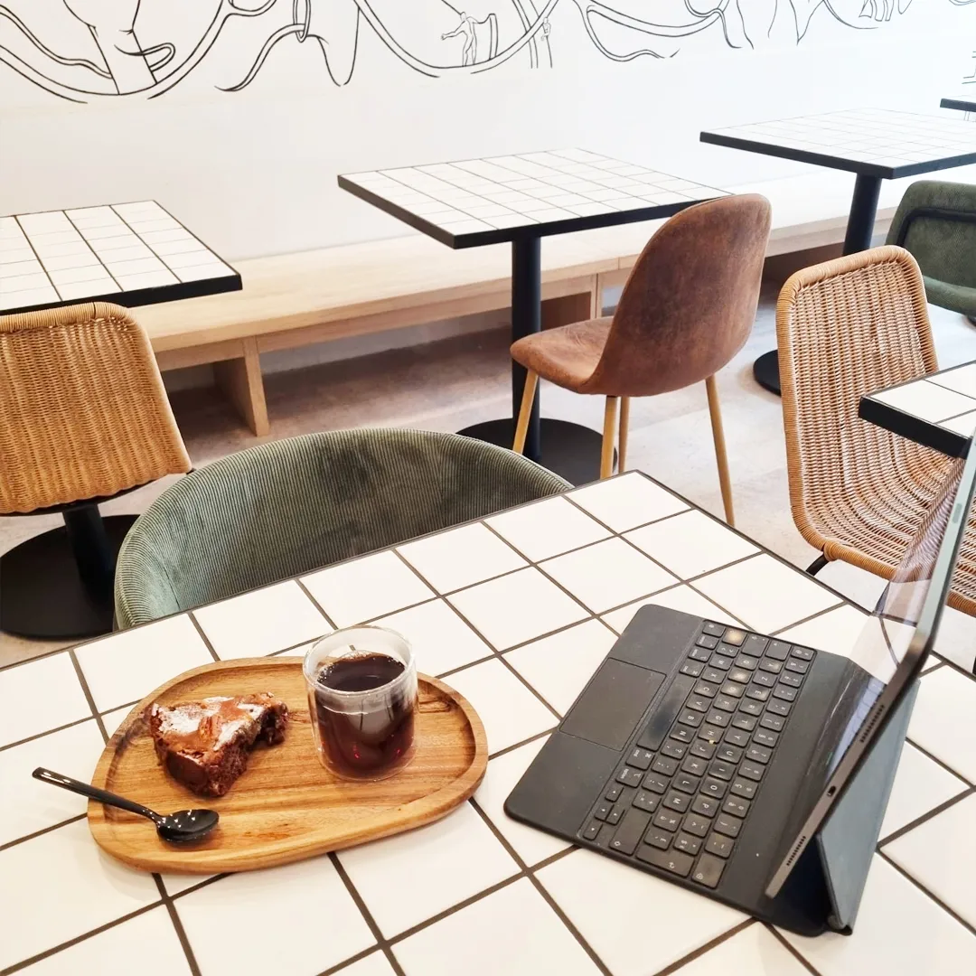 Client en coworking chez Mo:stera Marseille avec café noir, gâteau et tablette.